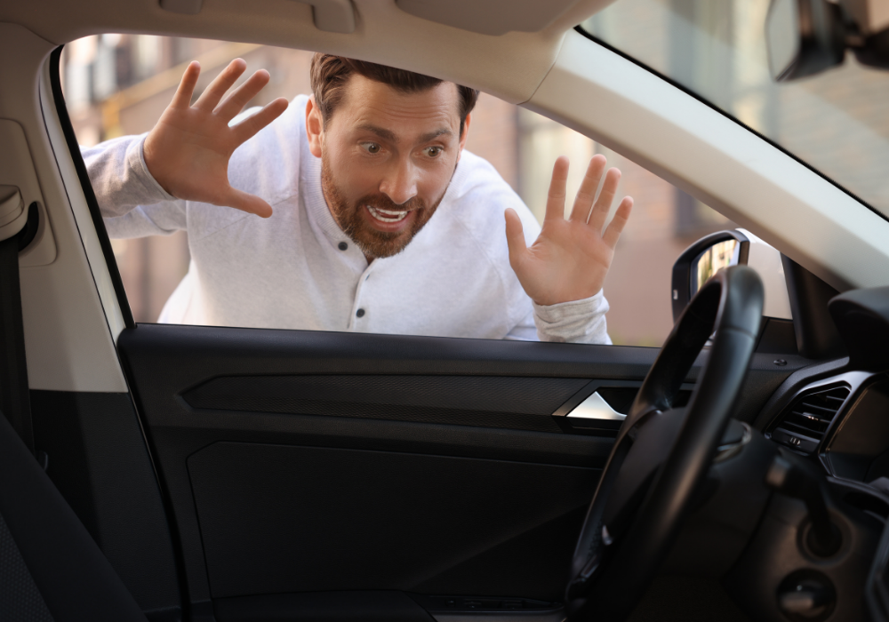 Man in a white shirt locked outside of his car looking inside his car with his hands pressed on the car window trying to get inside his car