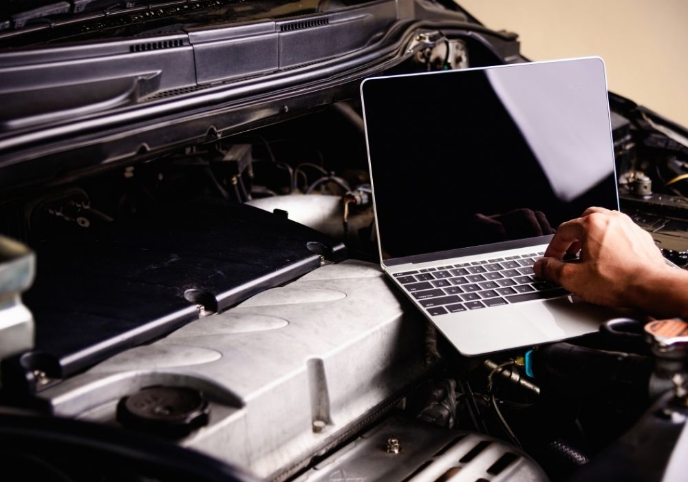Auto locksmith with a laptop working on ECU remapping of a vehicle to improve its performance