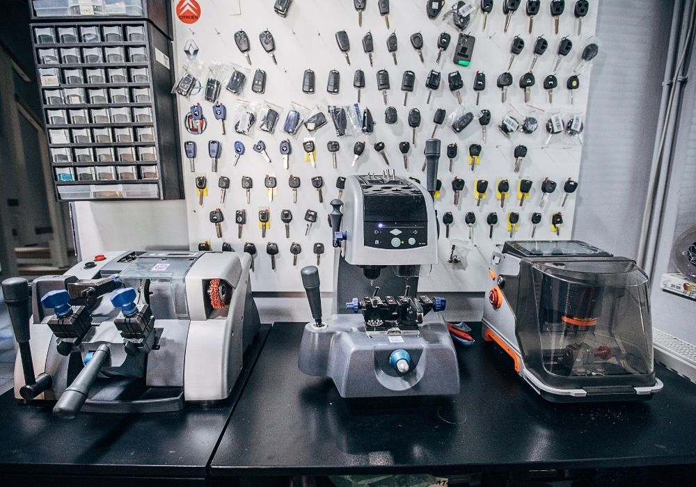 Auto locksmith garage with vehicle key programming equipment on a table with many different car keys hung on a wall