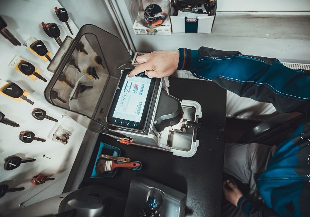 Professional auto locksmith in his garage programming car keys to their respective cars using his car key programming equipment